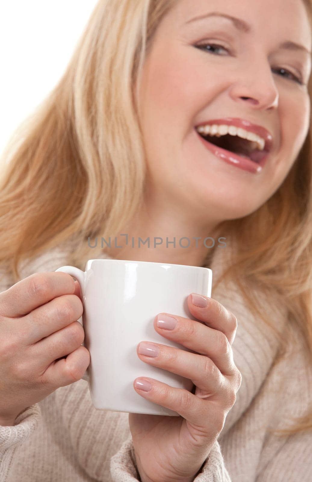 pretty blond woman wearing beige sweather drinking coffee