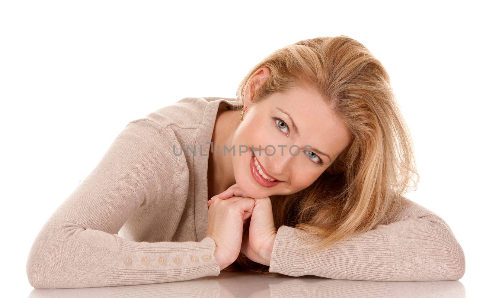 pretty blond woman wearing beige top sitting on white background