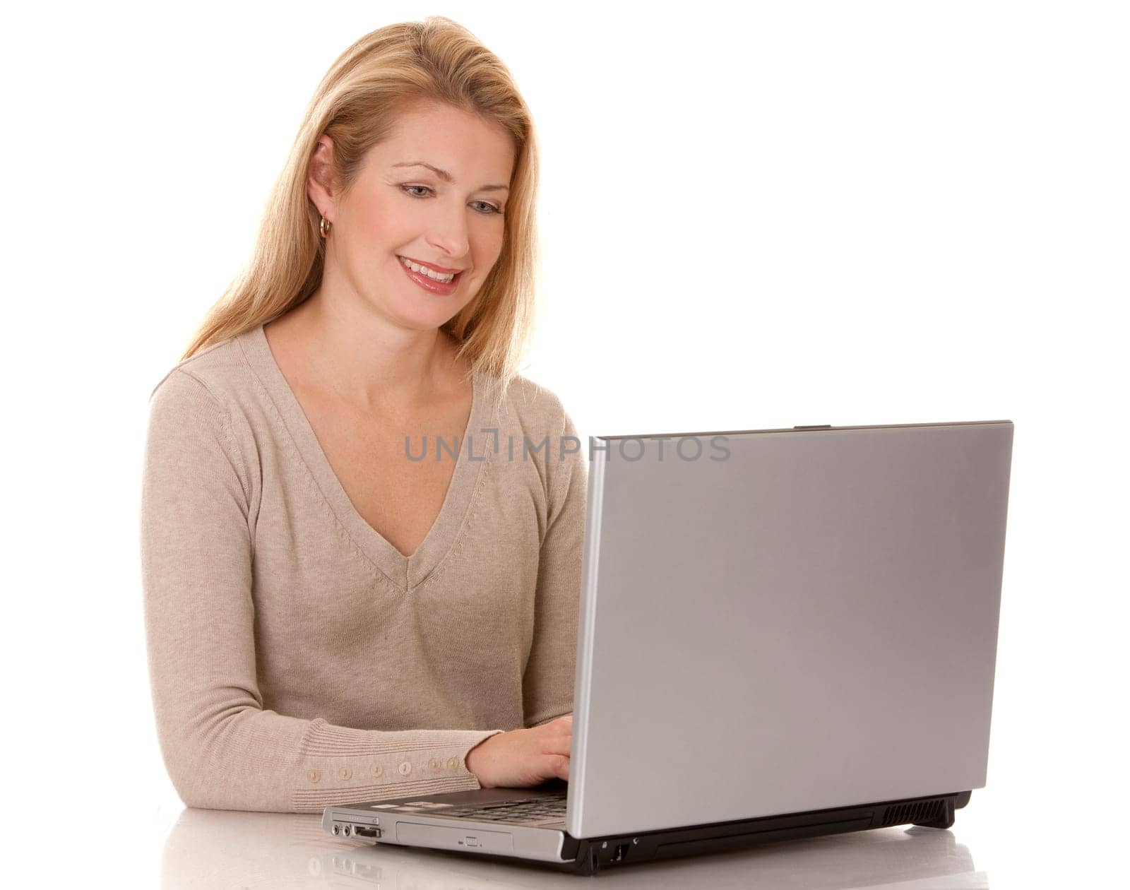 pretty blond woman wearing beige swether, sitting down and using laptop