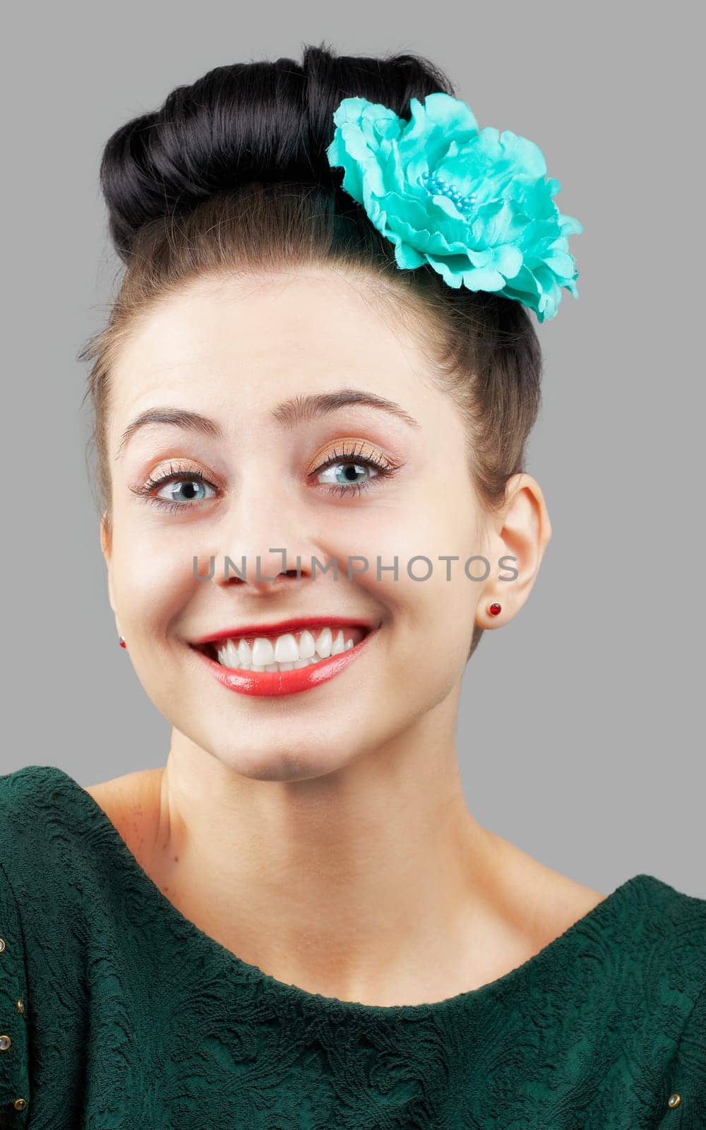 Portrait of a beautiful young woman with a flower in her hair isolated on grey