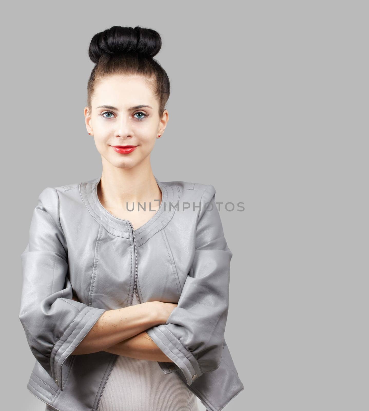 Portrait of a beautiful young woman with grey jacket over grey background.