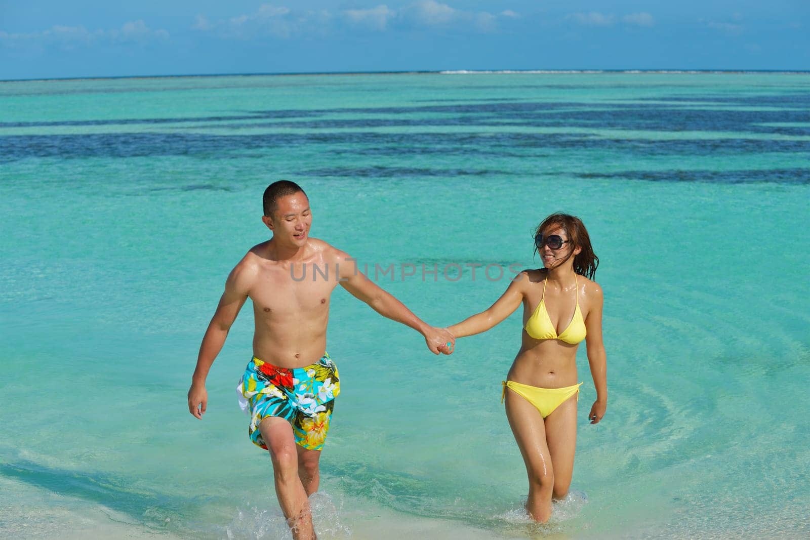 happy young asian couple enjoying summer and have on beautiful white sand beach