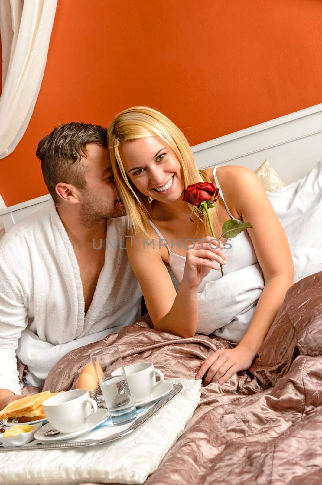 Cuddling couple cuddling bed motel room celebrating anniversary rose