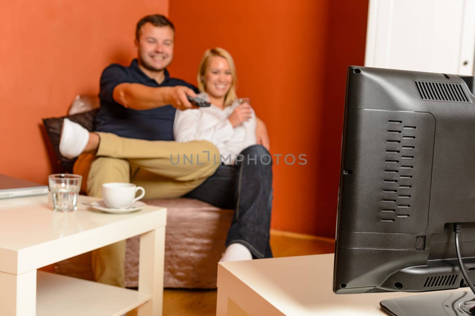 Happy couple watching tv evening relaxing changing channels remote control