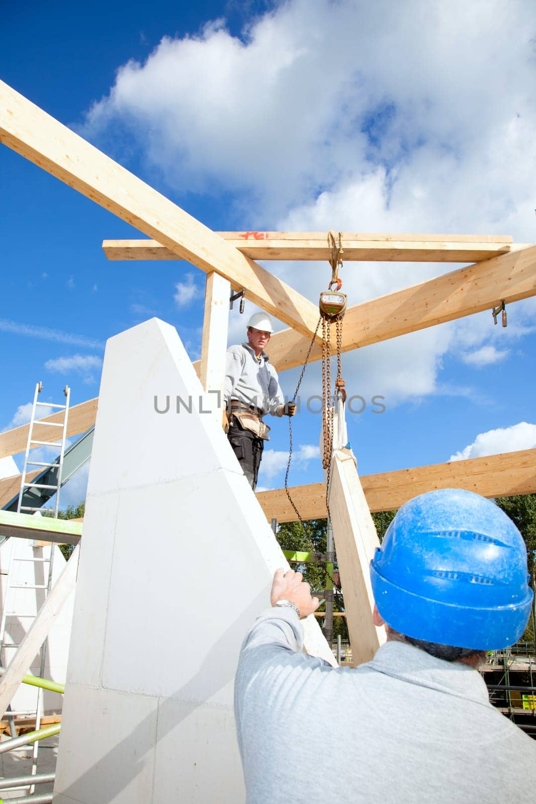 construction workers at work with wooden  roof construction of a new home