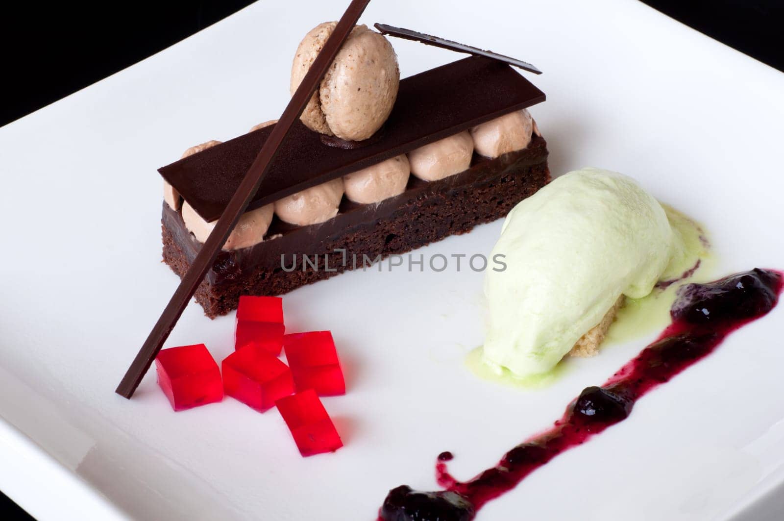Chocolate dessert and vanilla ice cream decorated with macaroon, raspberry jelly