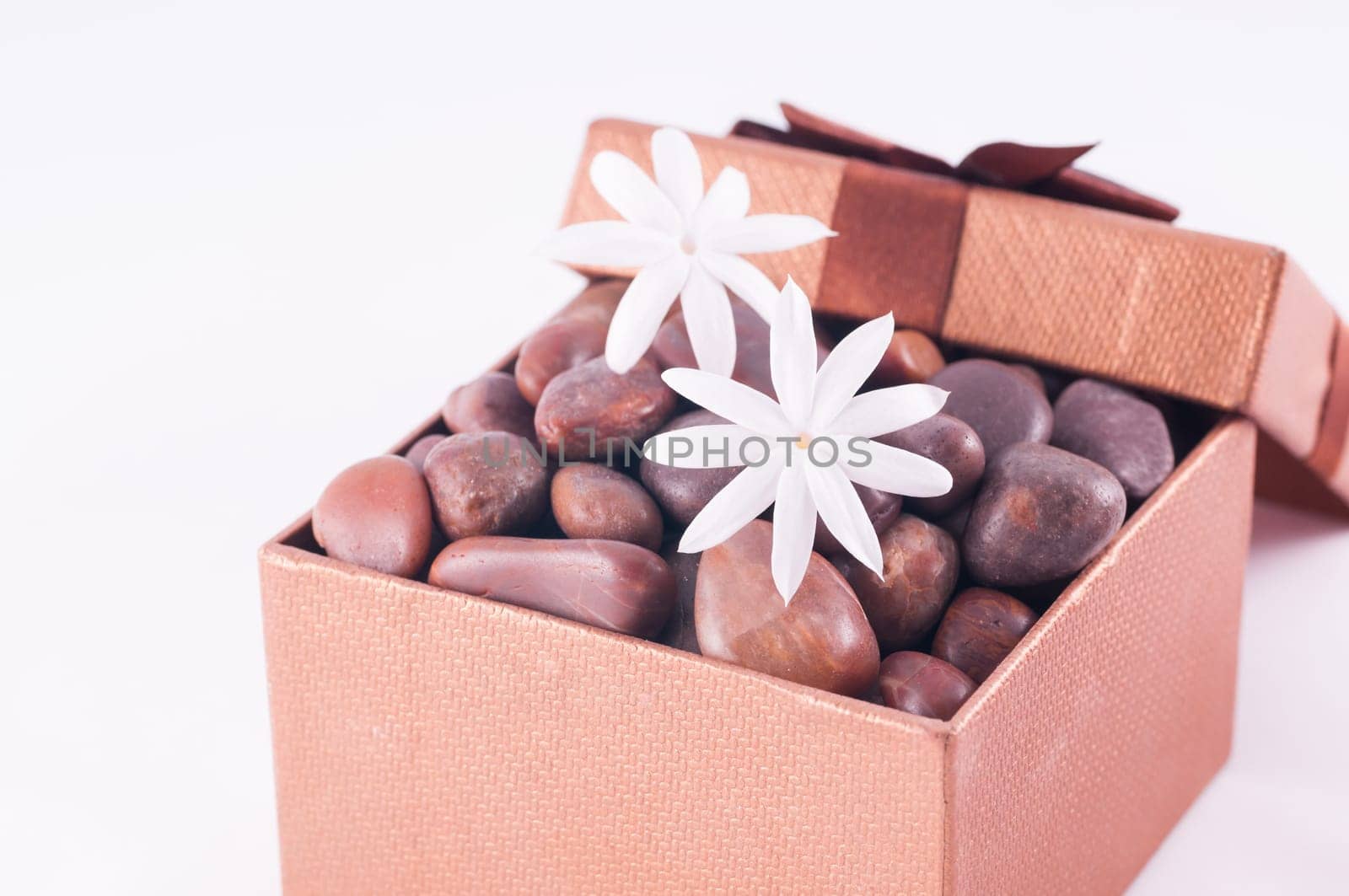 Spa concept - a gift of wellness with red zen stones and white jasmine flowers
