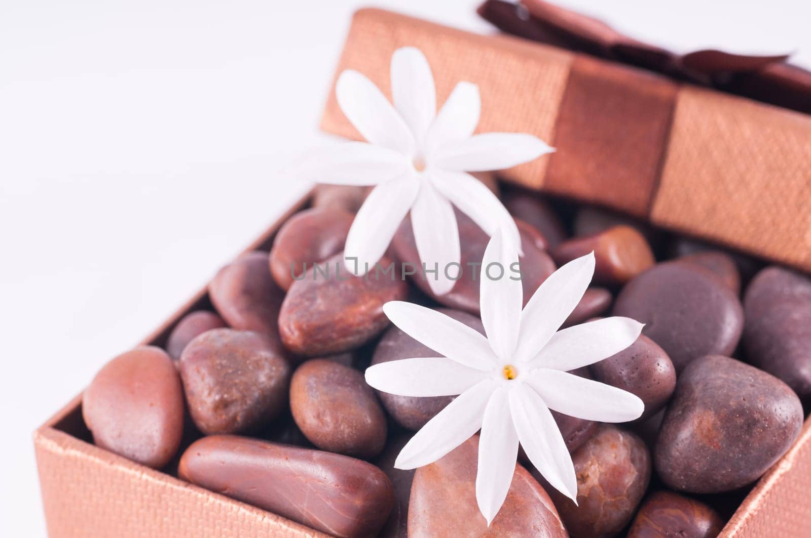 Spa concept - a gift of wellness with red zen stones and white jasmine flowers