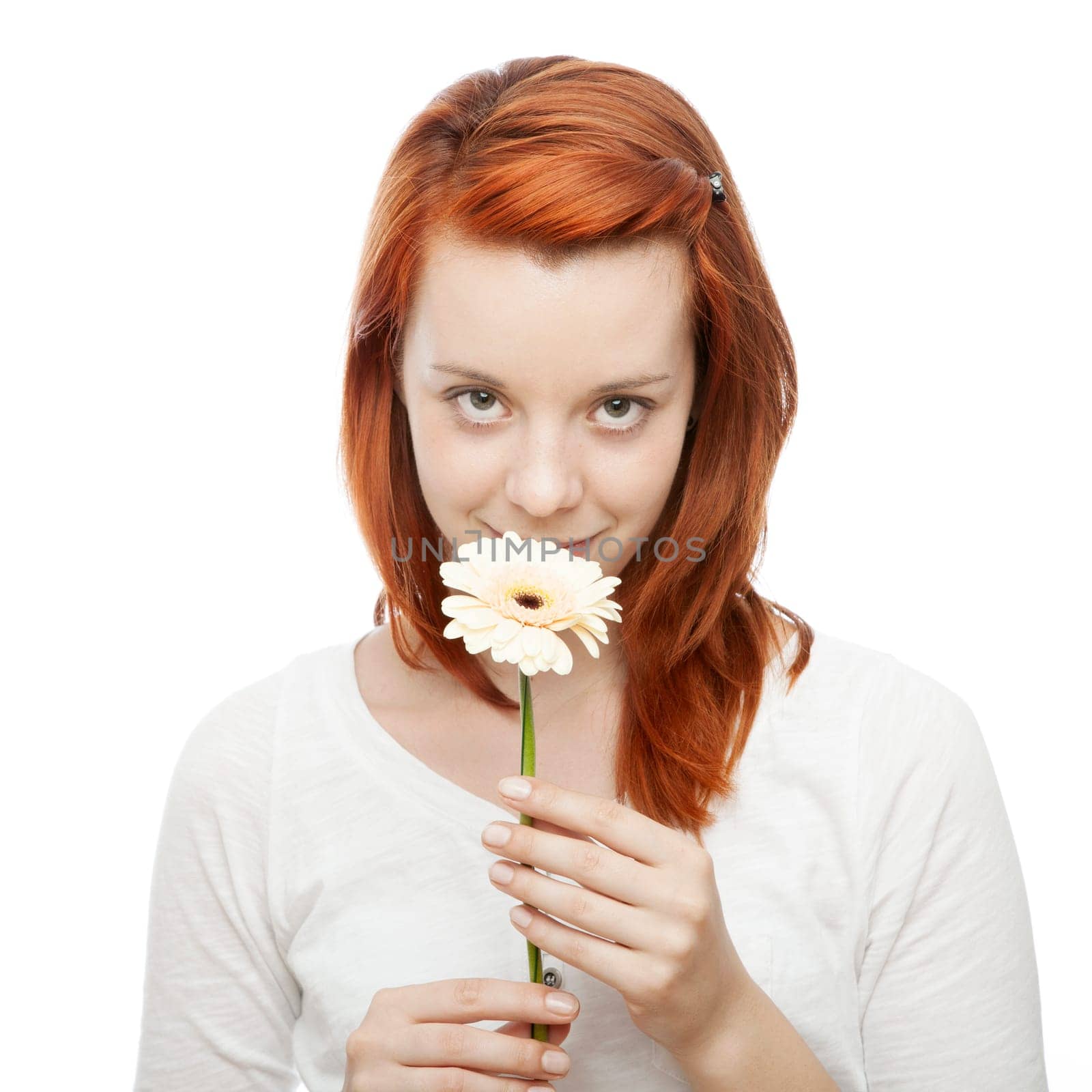 young beautiful red haired girl smelling on a flower in front of white background