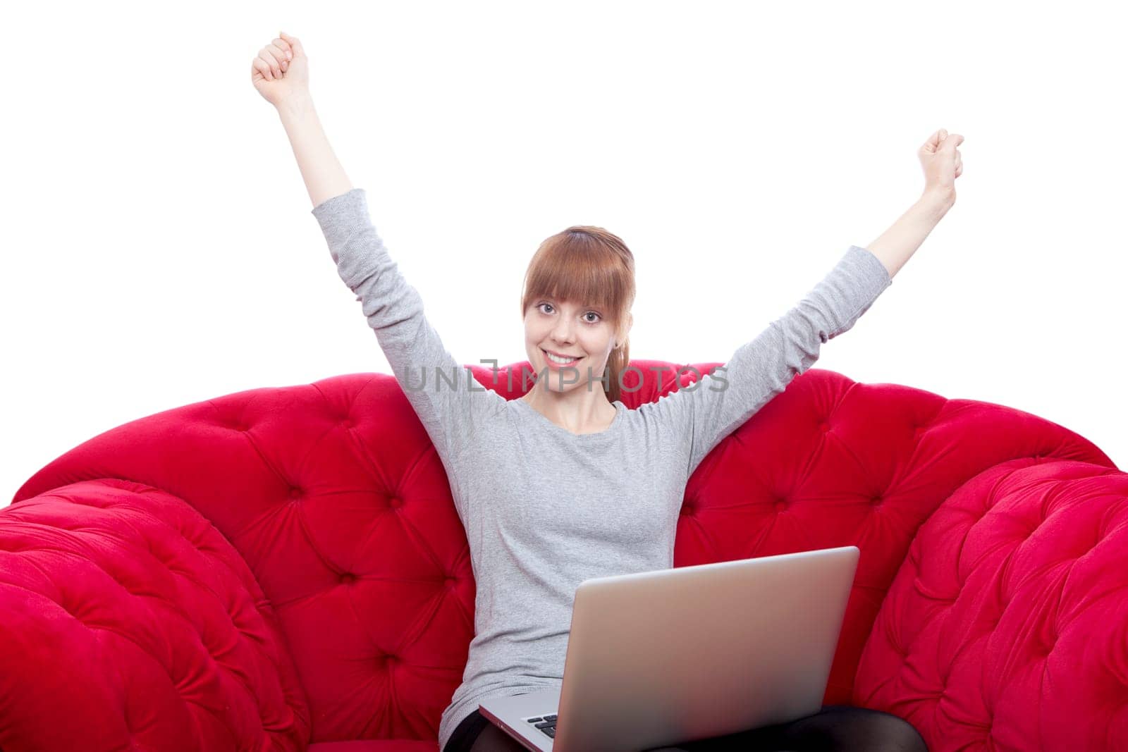young beautiful red haired girl on red sofa raise arms in the air in front of white background