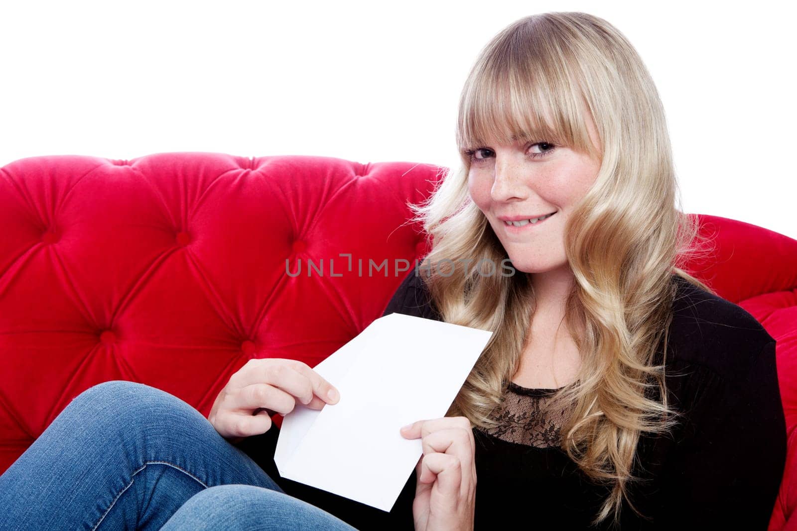 young blond haired girl has a romance and got a letter on red sofa in front of white background