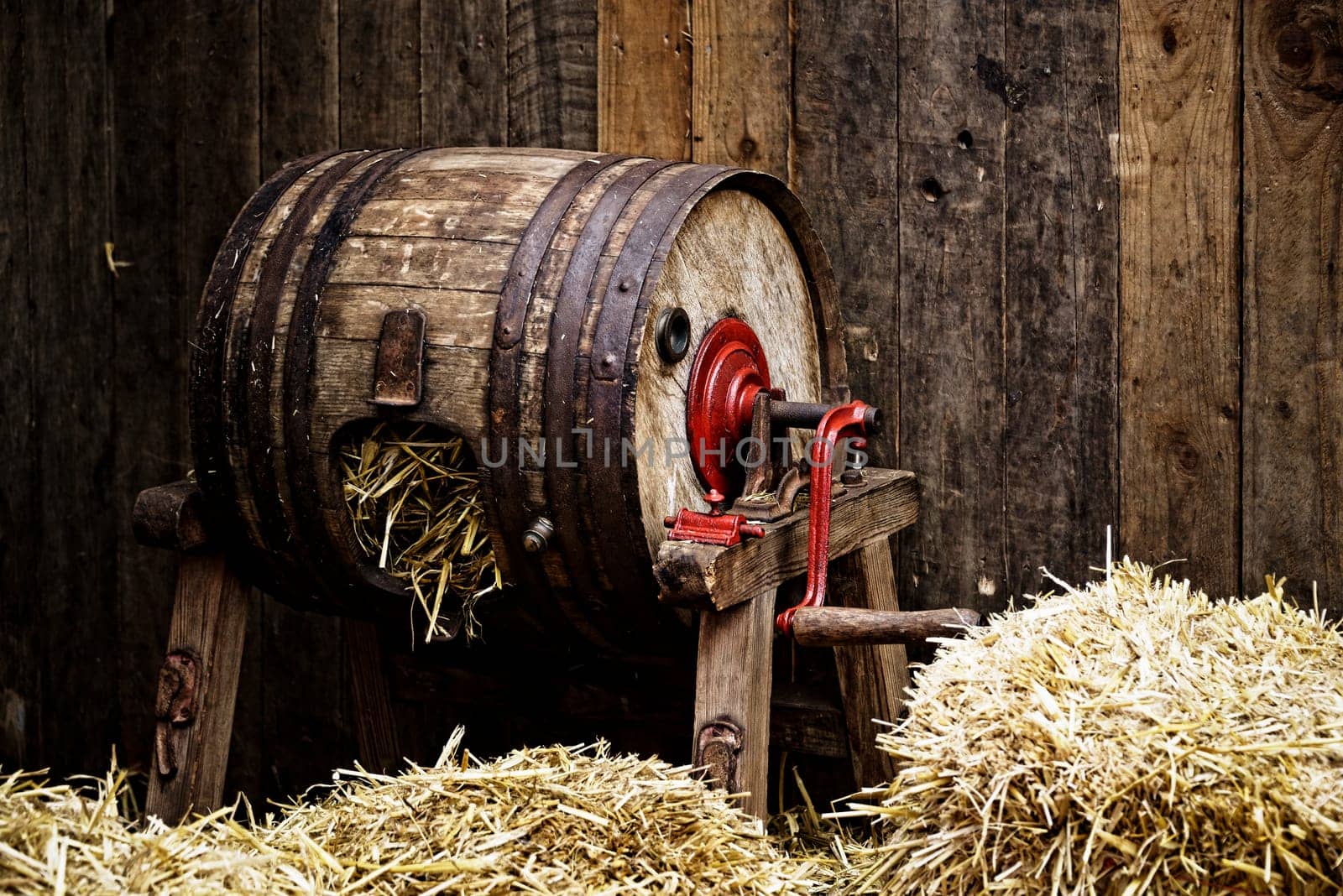 Vintage barrel-type butter churn filled with straw, wooden background