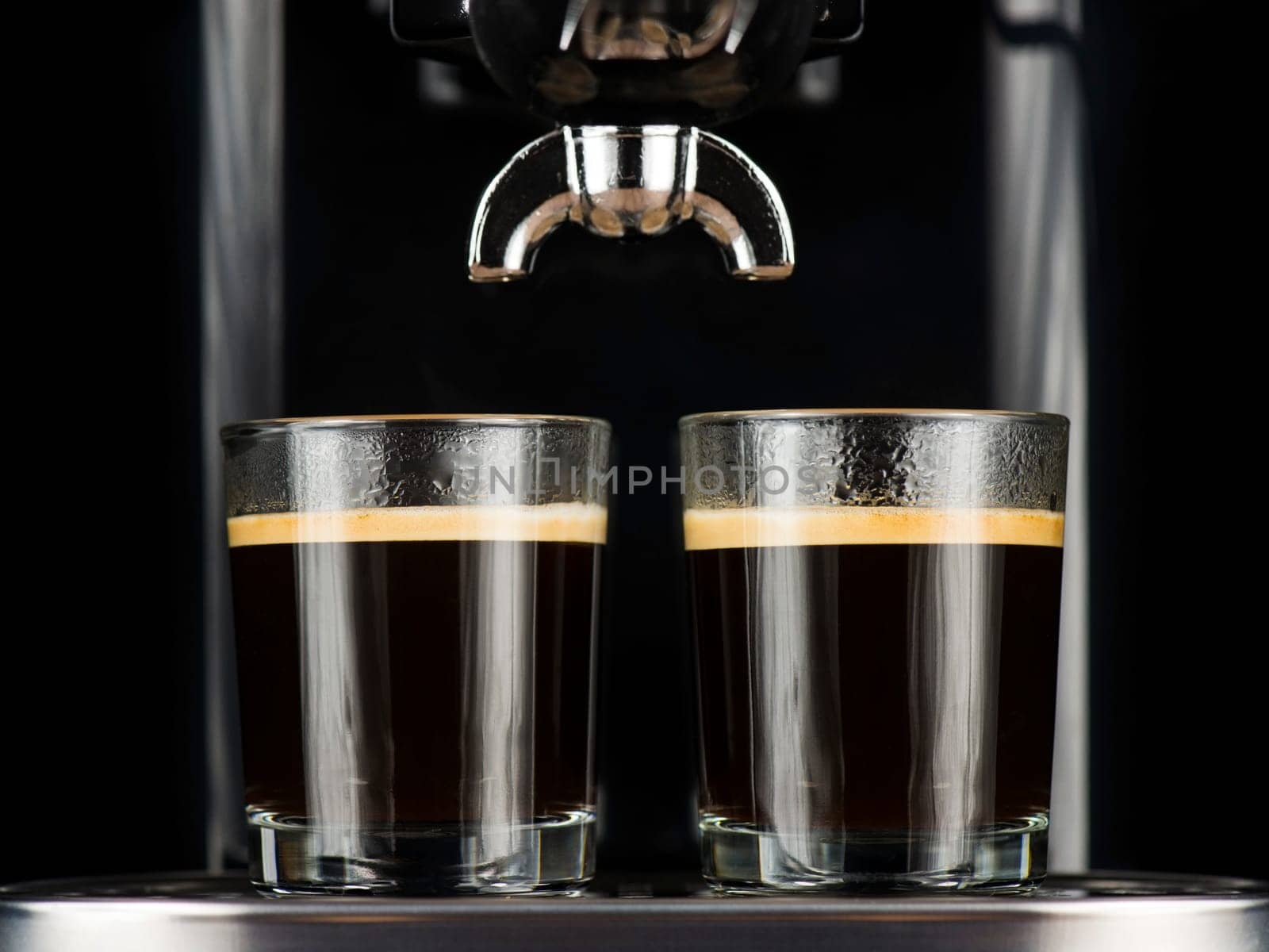 Two espresso cafes served in glasses under the percolator