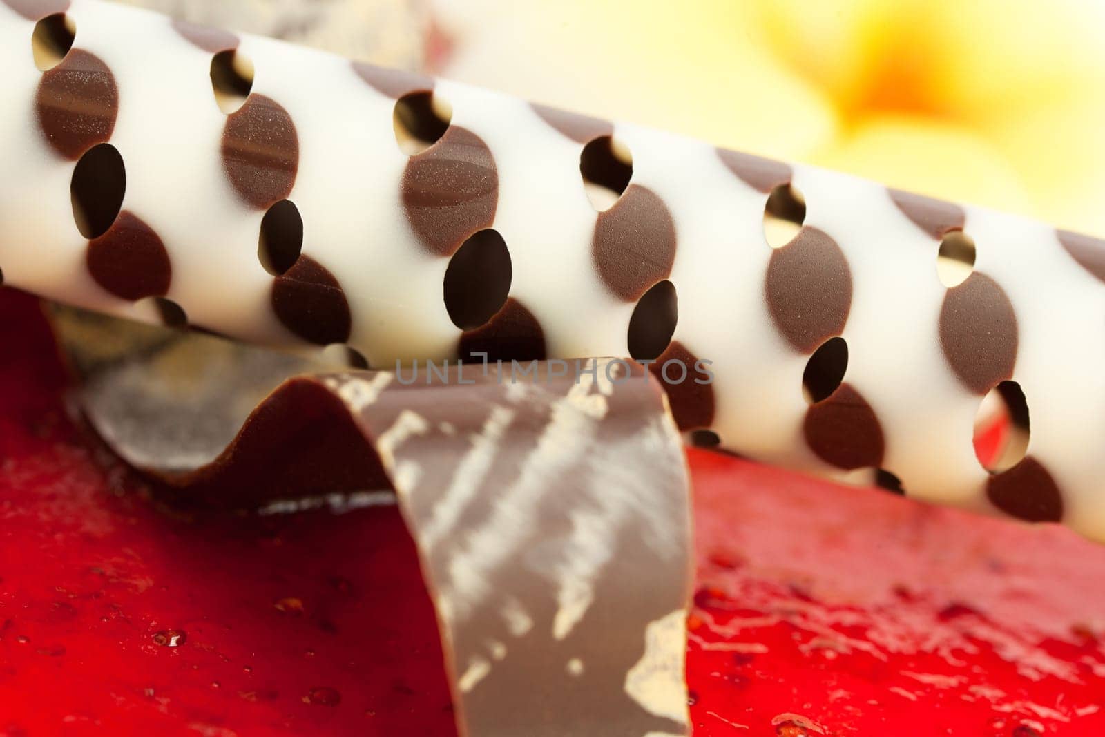 Decoration with a chocolate tube over strawberry jelly.