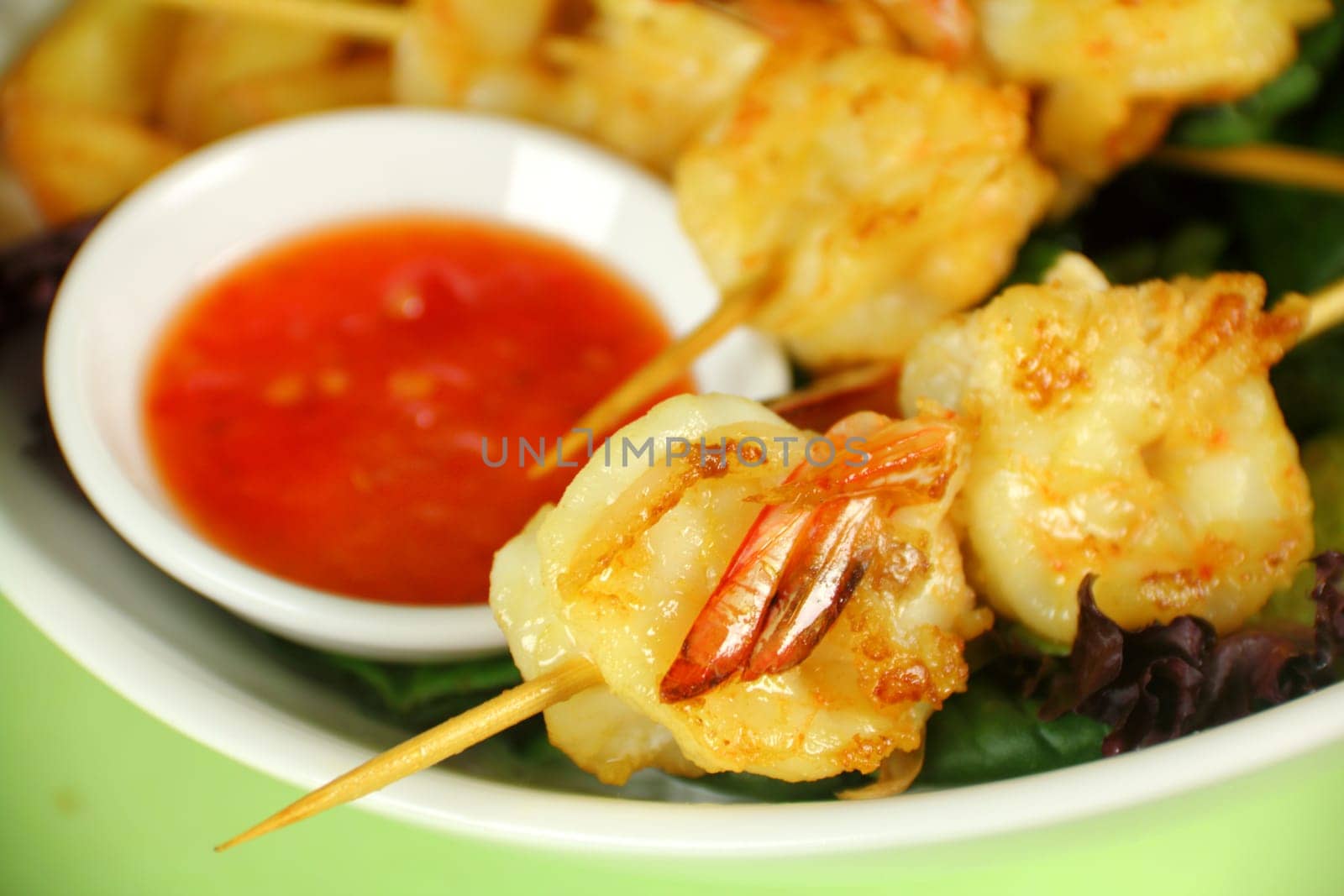 Yummy fried shrimp skewers with chunky chips with sweet chilli sauce ready to serve.