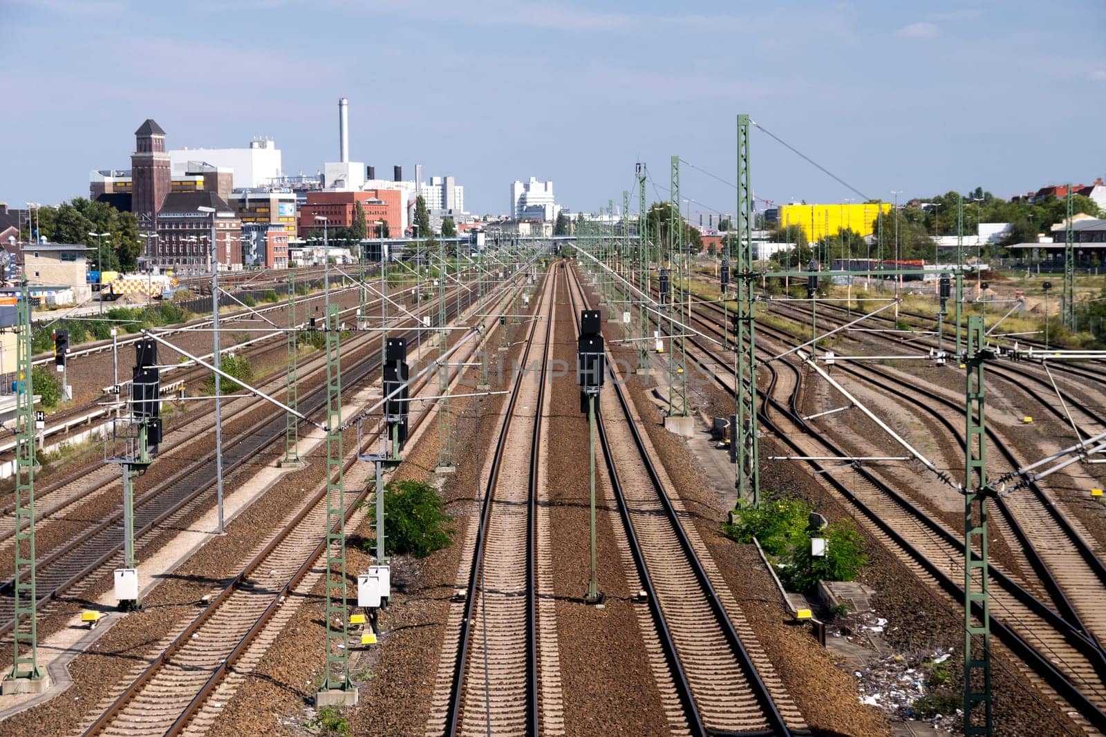 railroad tracks near a station, in the background industry buildings.