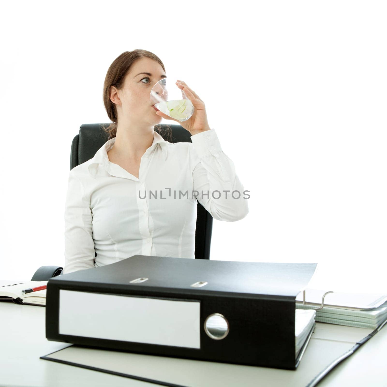 young brunette woman drinking water in front of documents
