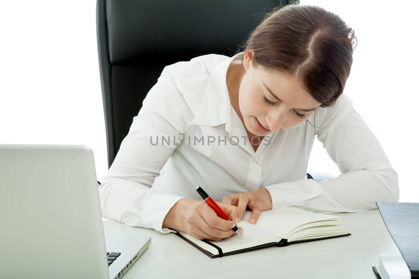 young brunette business woman writing text with pen in book