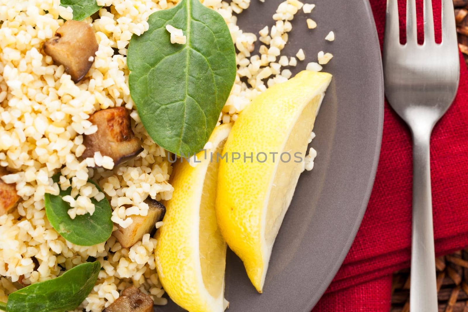 Bulgur salad with spinach roasted eggplant and a lemon wedge