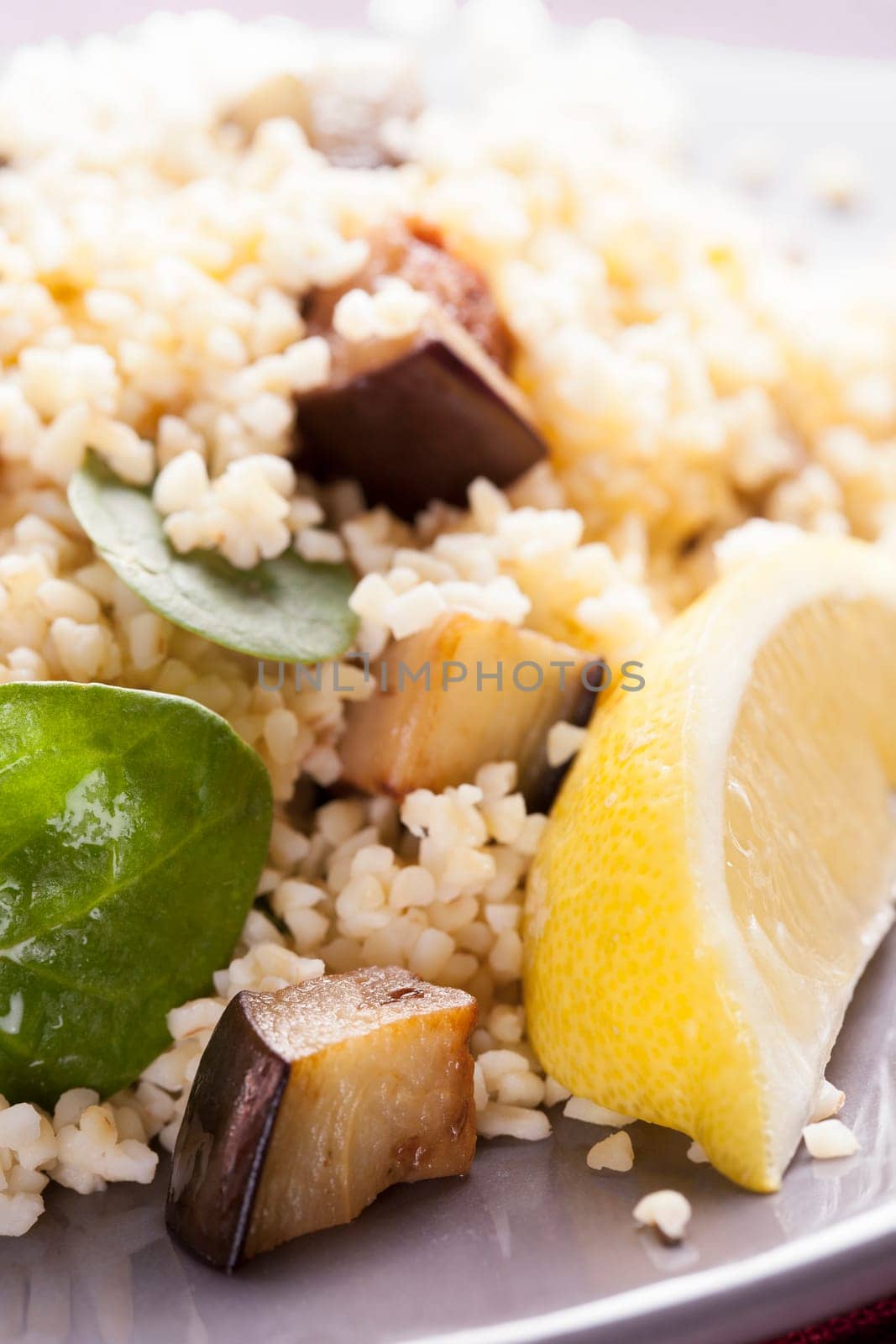 Bulgur salad with spinach roasted eggplant and a lemon wedge