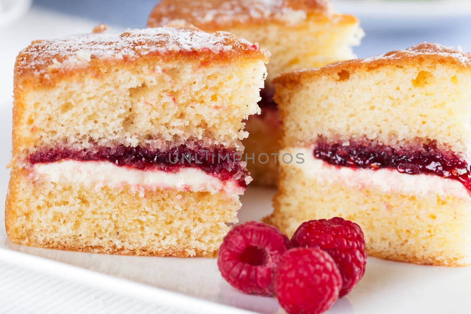Victoria sponge cake with cream and jam filling, served with raspberries