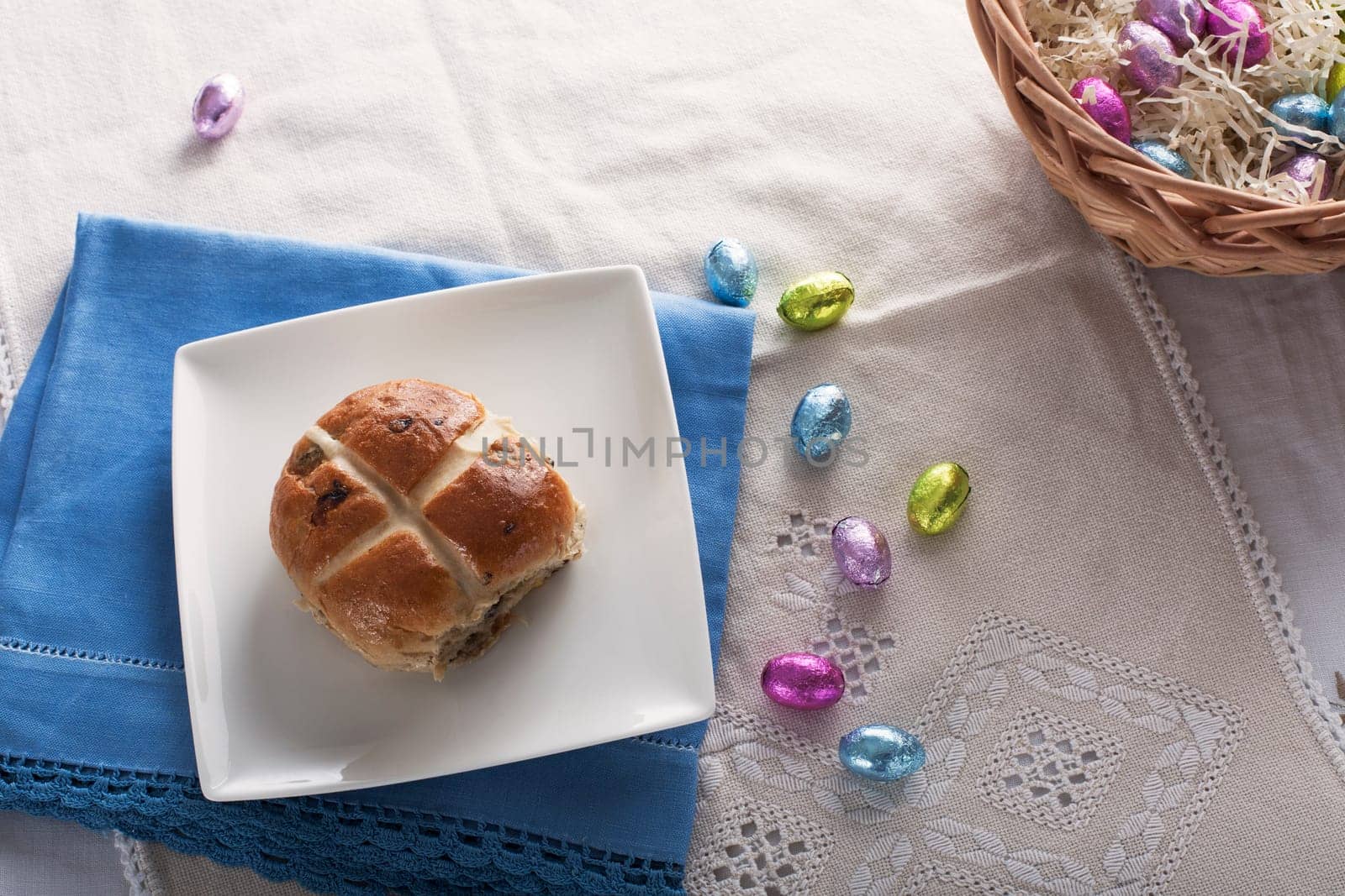 Hot cross bun from above with chocolate easter eggs