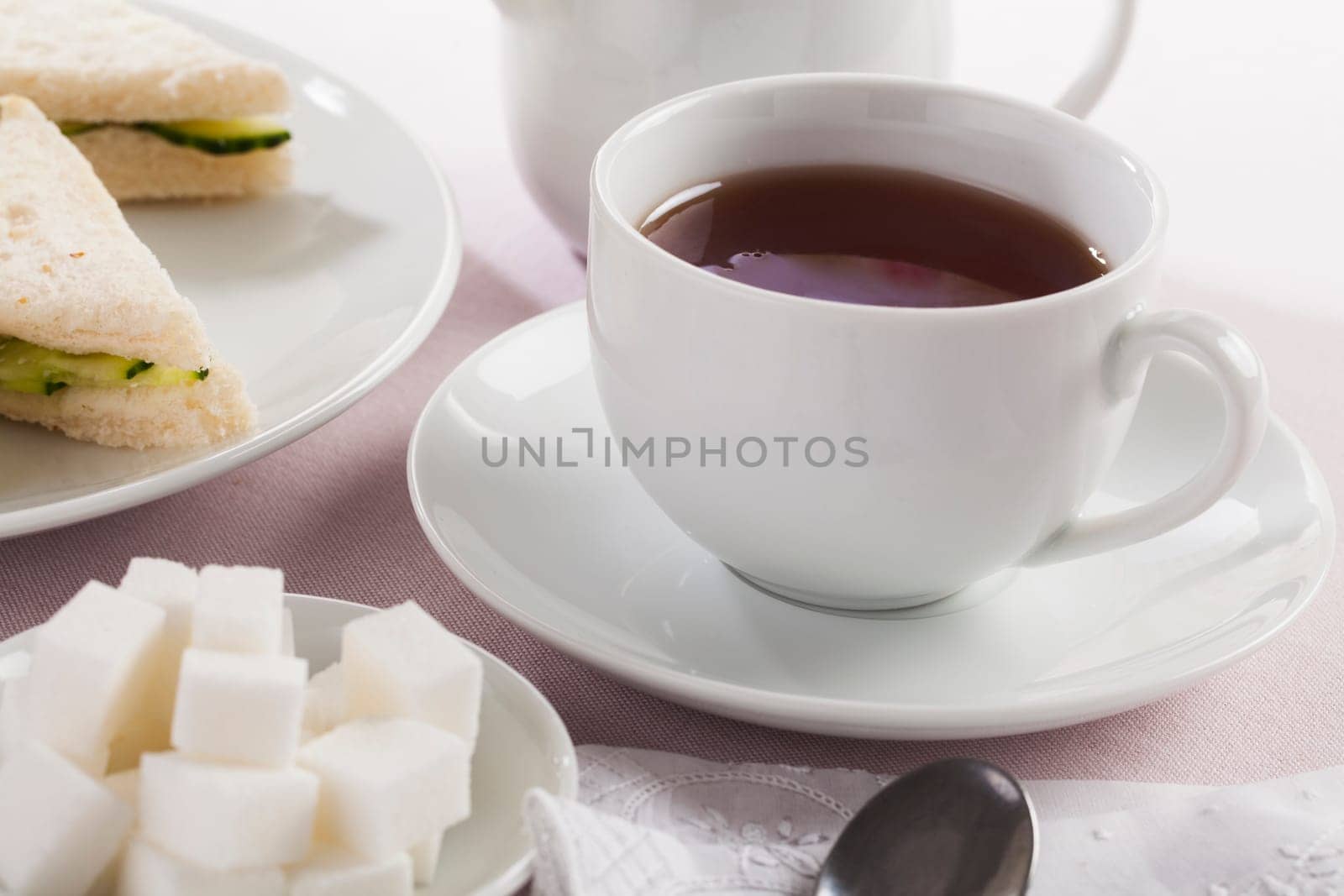 Cup of tea with sugar cubes and other afternoon tea treats