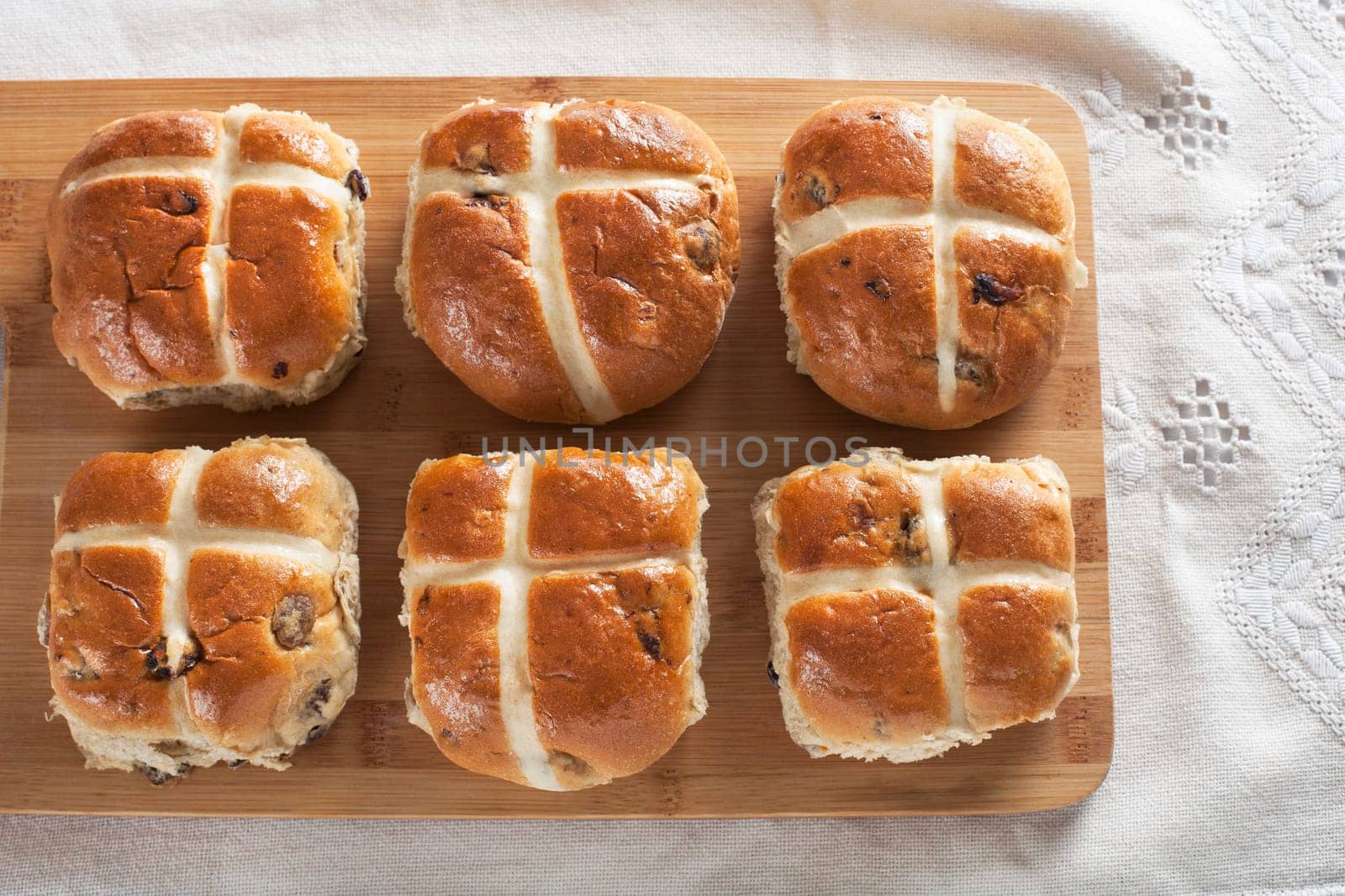 Six hot cross buns on a wooden cutting board