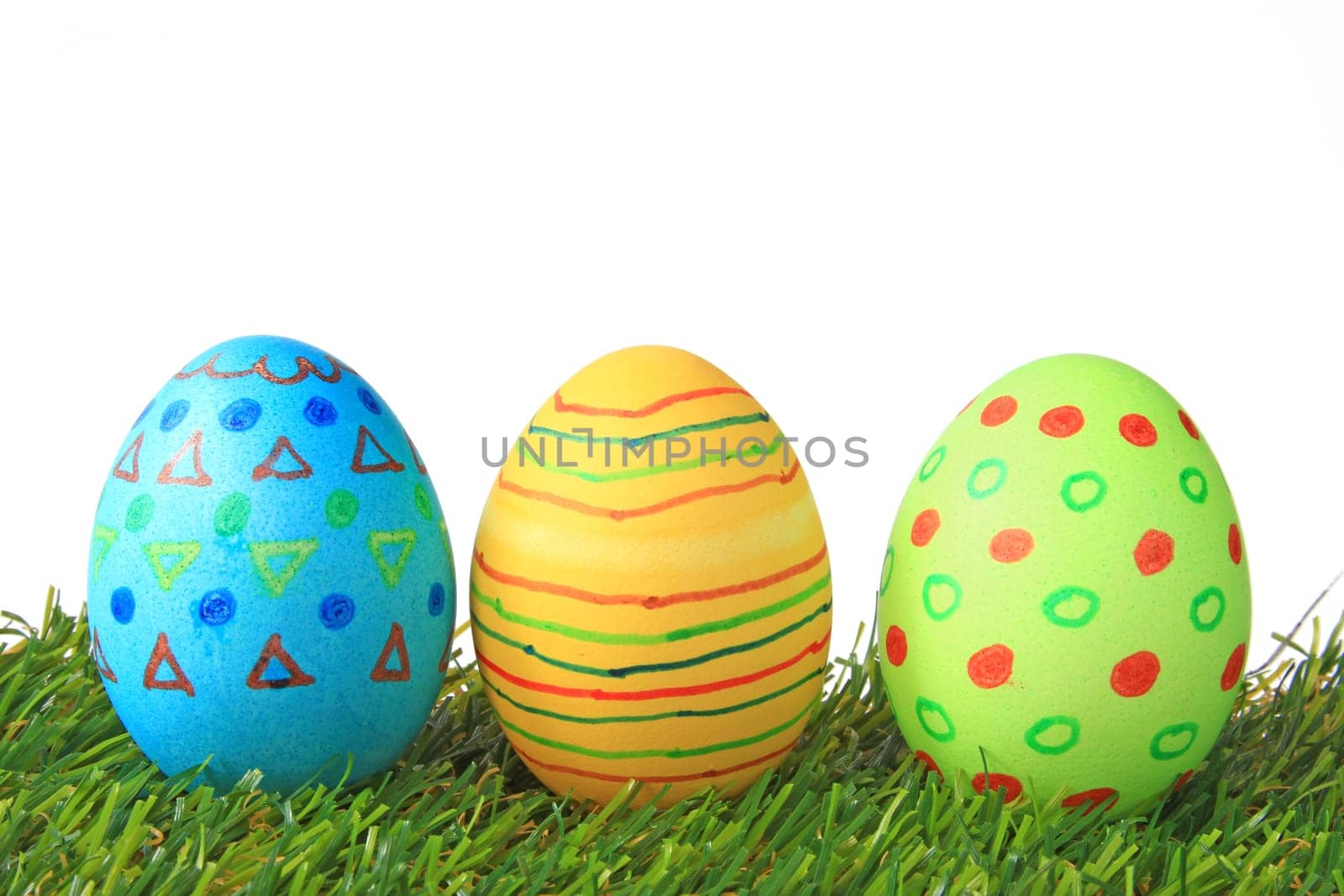 Colorful colored easter eggs on artificial grass against white background