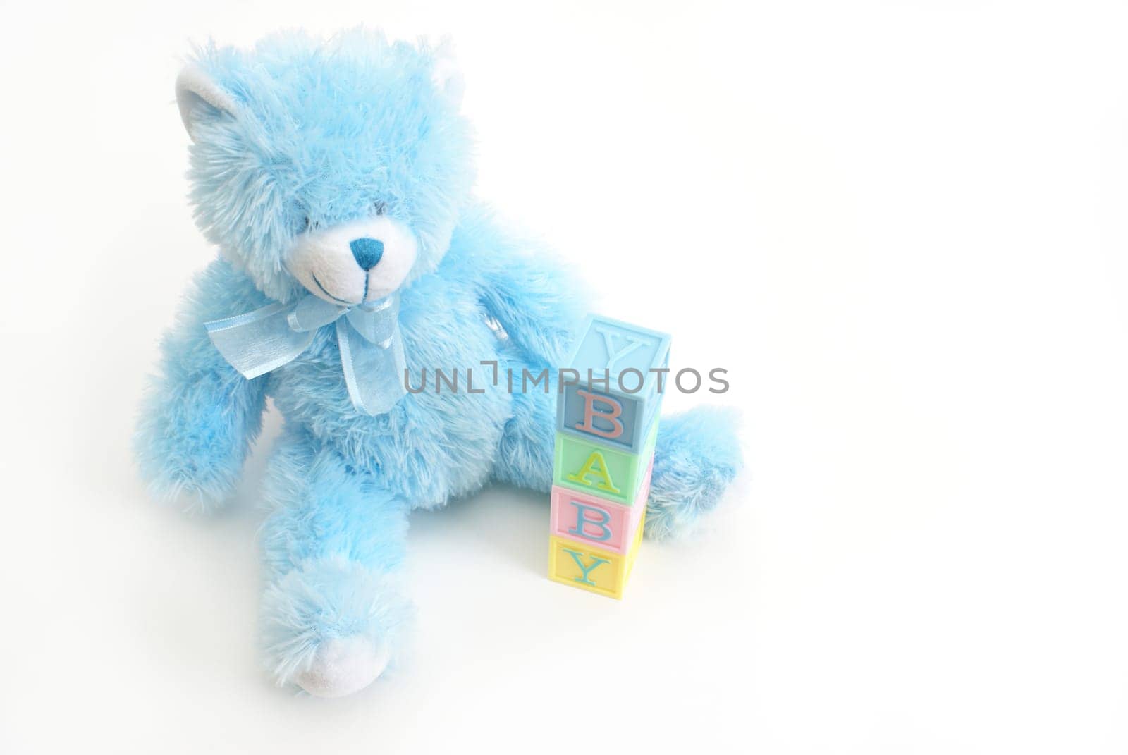 A blue teddy bear sits next to the word baby.