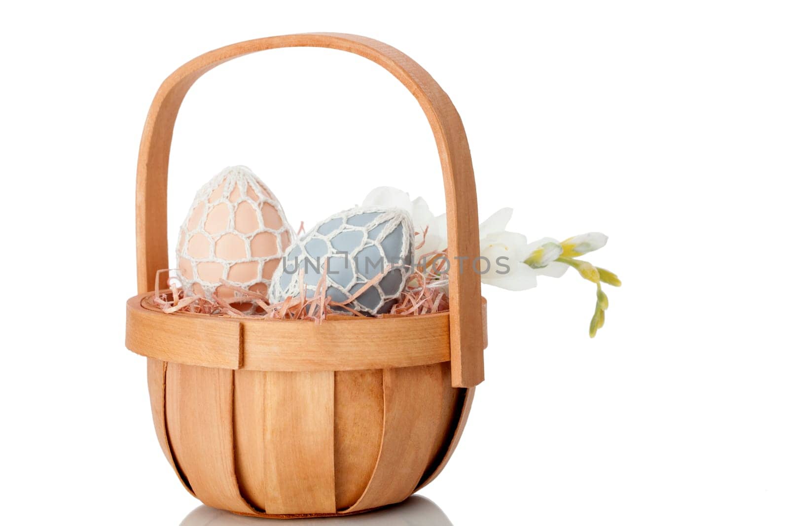 Rustic Easter Egg gift in a quaint little cane basket with a fresh white spring flower on a white studio background