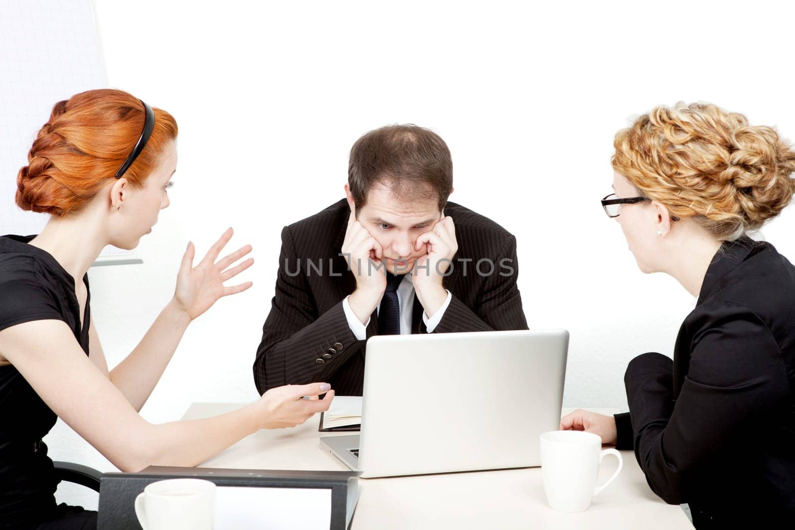 Business team in a serious meeting with the male leader staring dejectedly at his laptop while a female colleague explains something gesturing with her hands