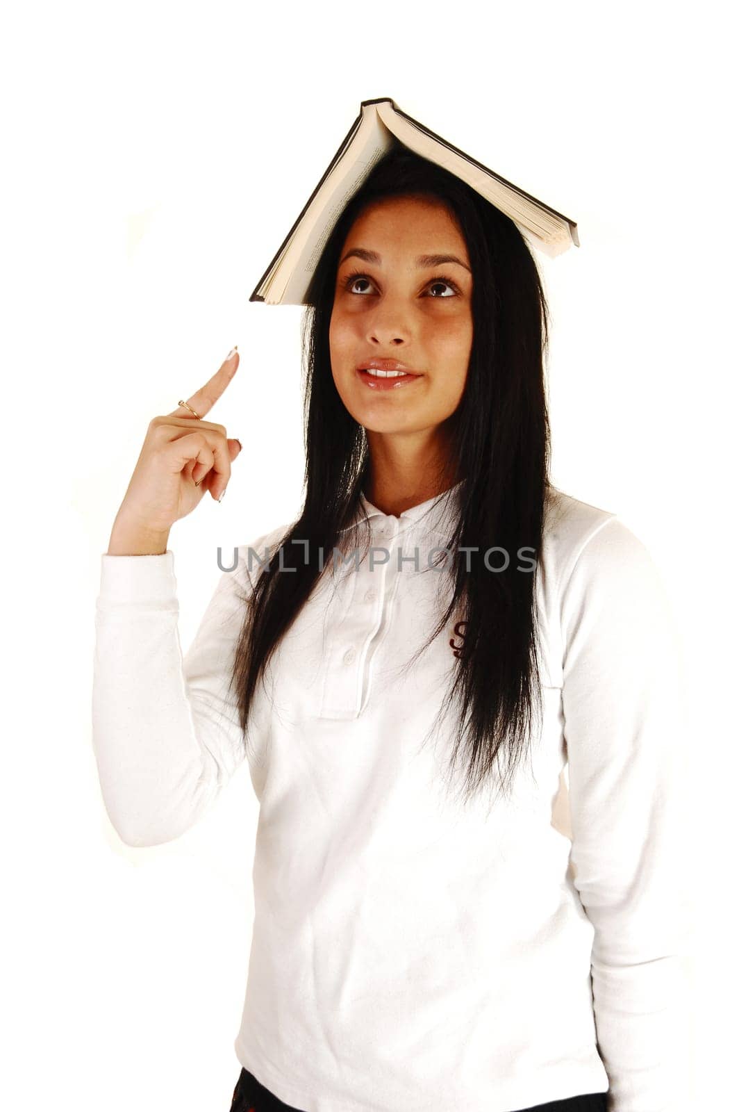 A lovely teenage girl in her school uniform with a book on top of her head standing for white background with her long black hair.
