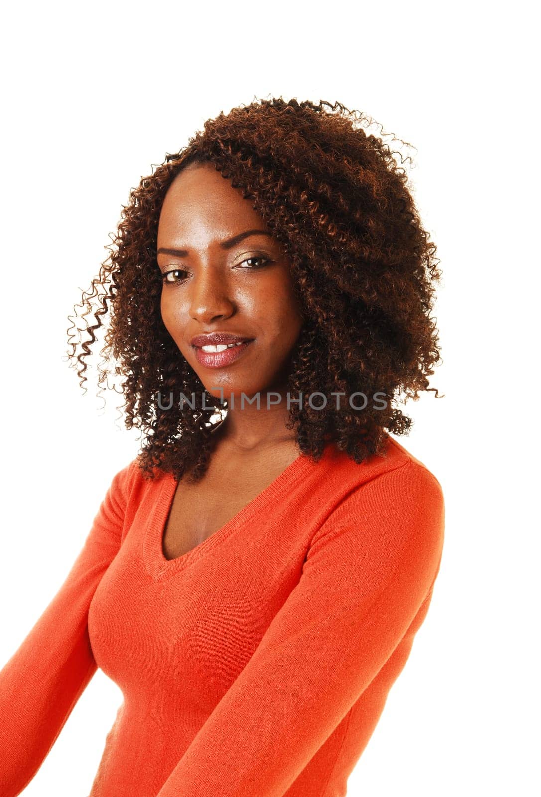 A portrait of a beautiful African American teenager, sitting with her long curly brown hair, in a orange sweater, for white background.