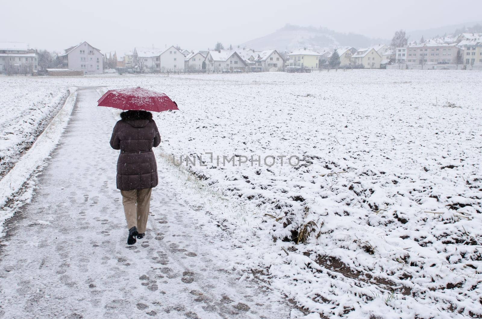 Woman with red umbrella doing walking in the snow