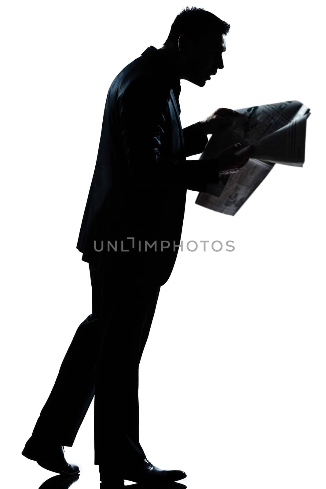 one caucasian man walking reading newspaper surprised  full length silhouette in studio isolated white background