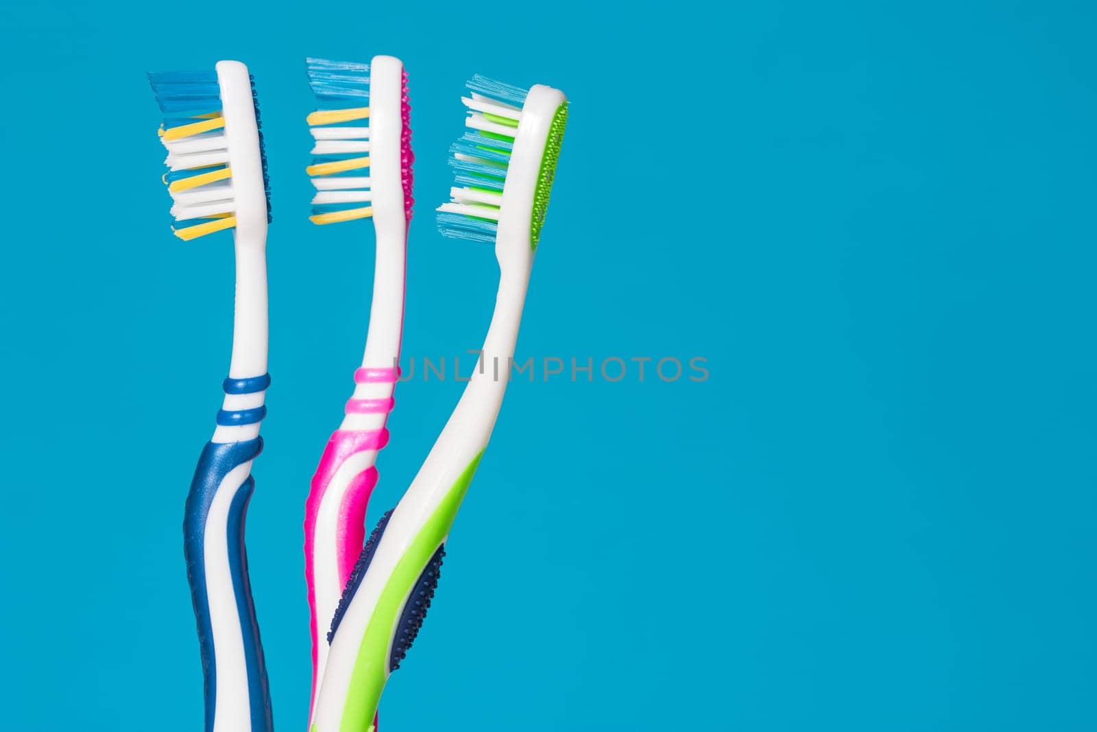 Three tooth brushes on the blue background