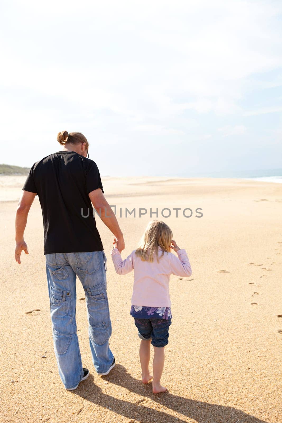 Father and daughter spending holiday time walking together at beach in Portugal