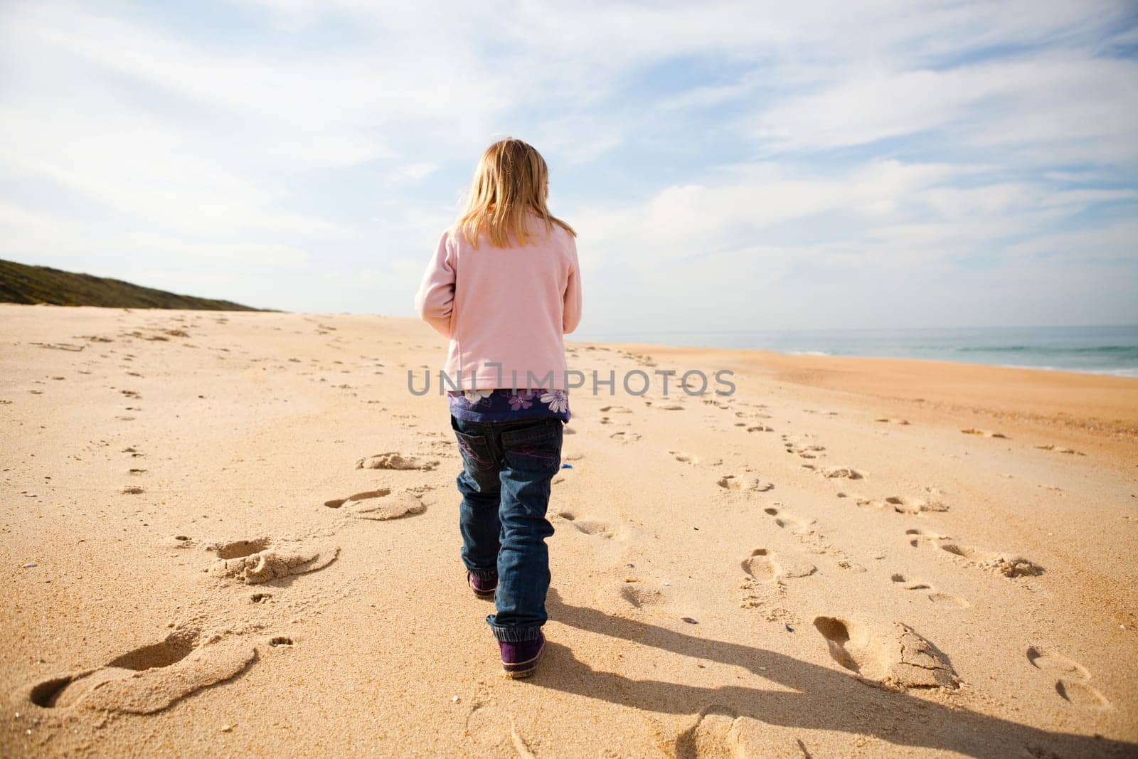 Young girl walking barefoot on beach while on holiday in Portugal
