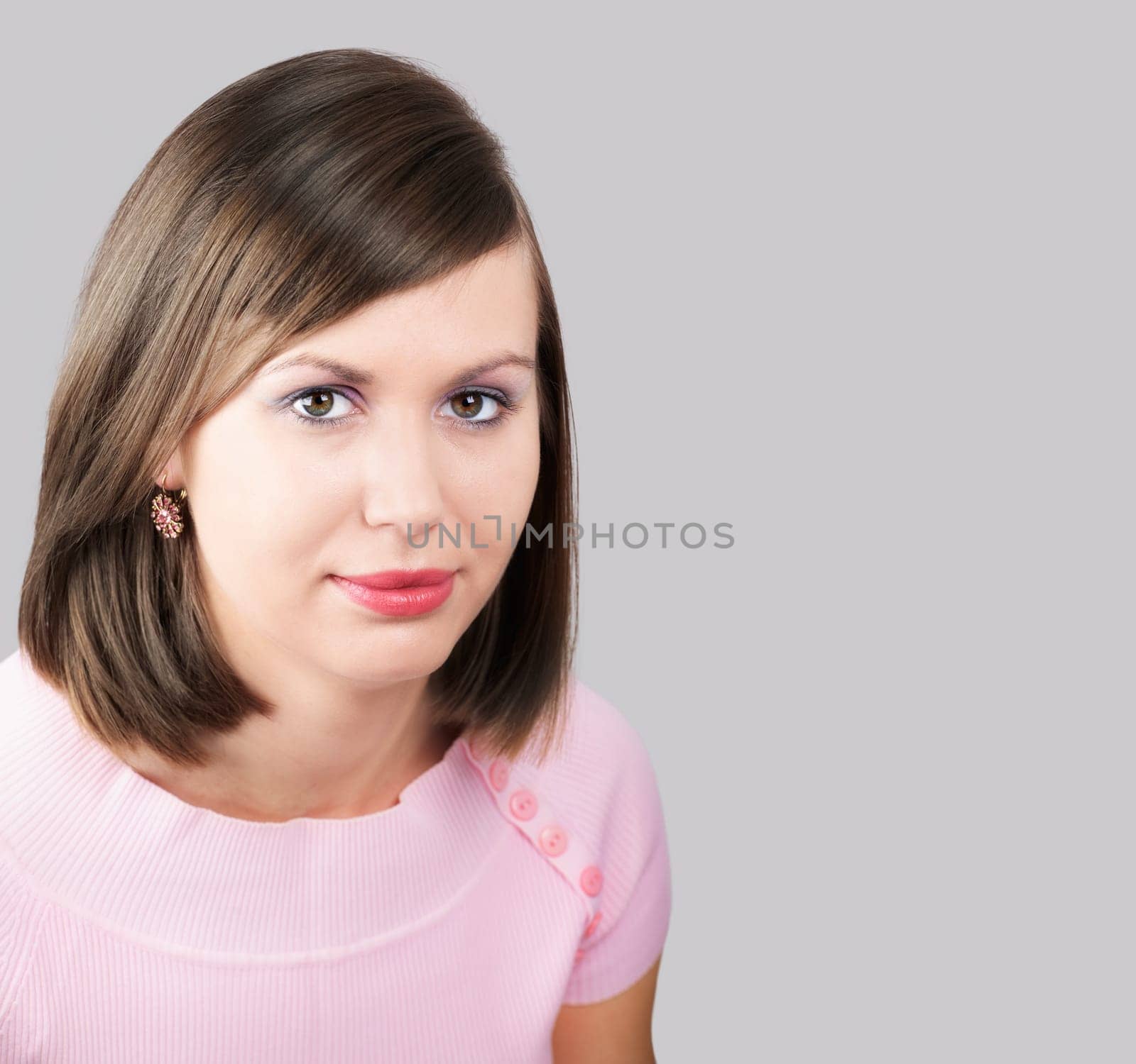 Portrait of a beautiful young woman with a pink top isolated on grey