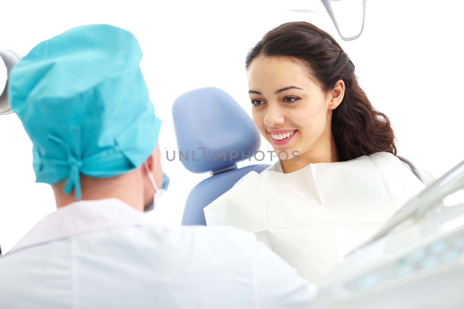 Young woman sitting in a dental chair and looking at doctor