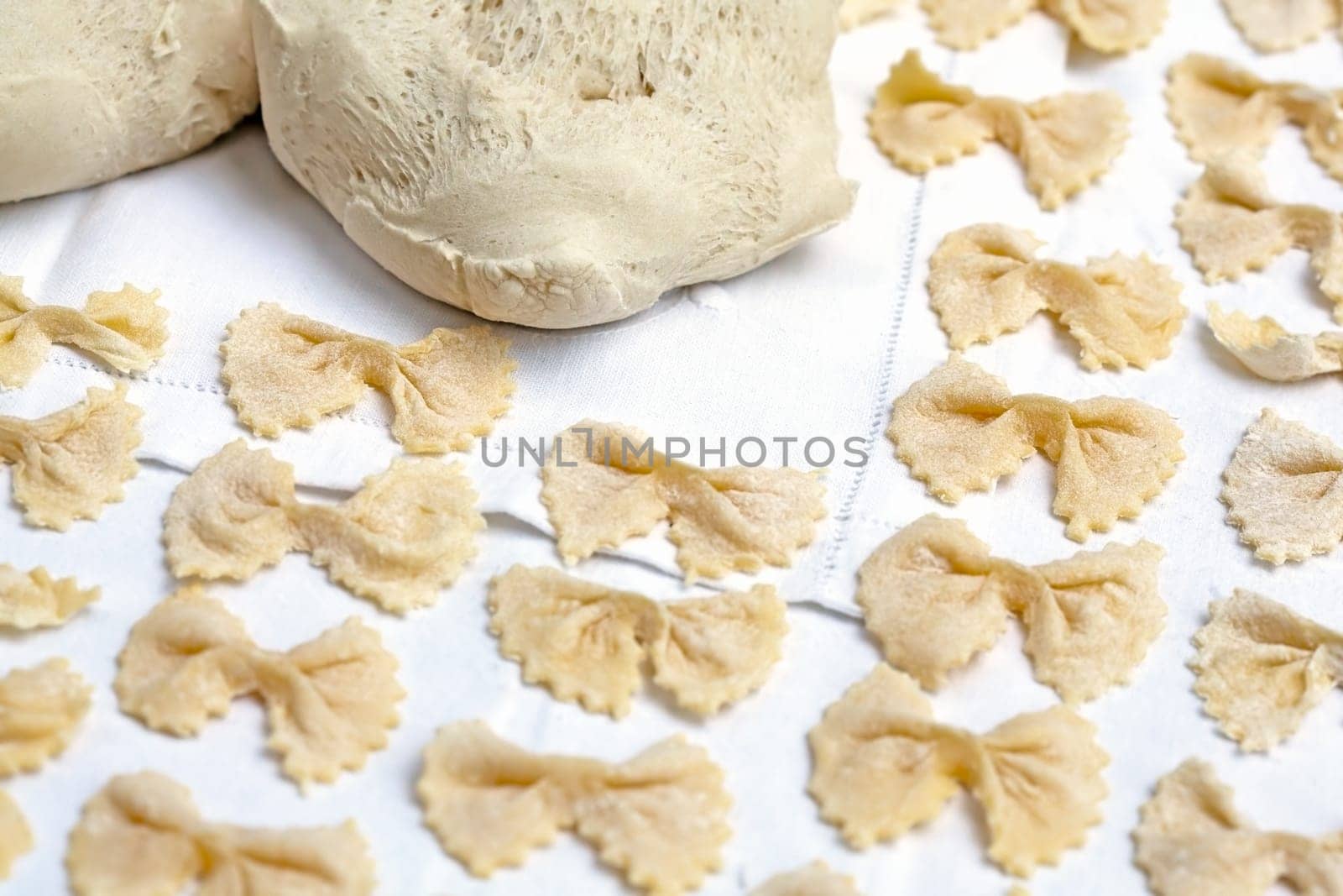Raw handmade pasta in shape of bow tie over a white table cloth. Traditional italian cuisine.