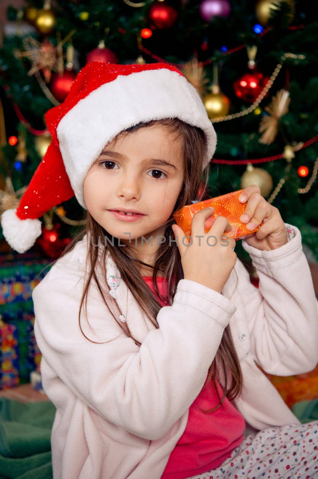 Cute little girl sitting in front of christmas tree