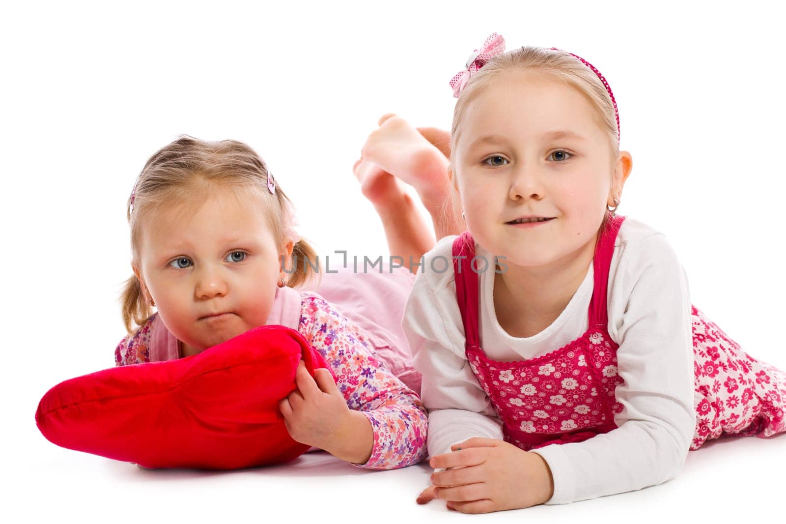 two sisters lying on white floor in studio
