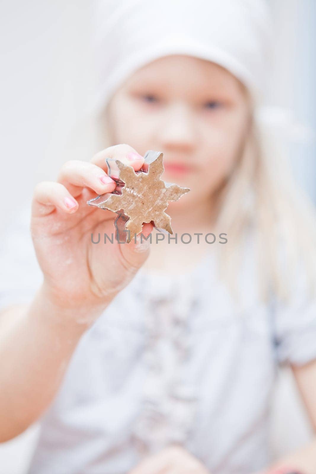 Young girl showing star shaped piece of dough for making gingerbread biscuits