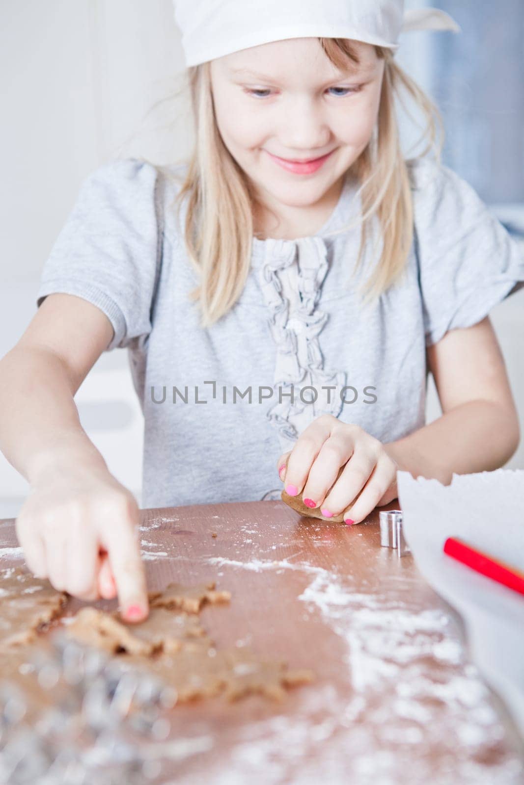 Happy smiling young girl pointing to star shaped piece of dough for making gingerbread biscuits