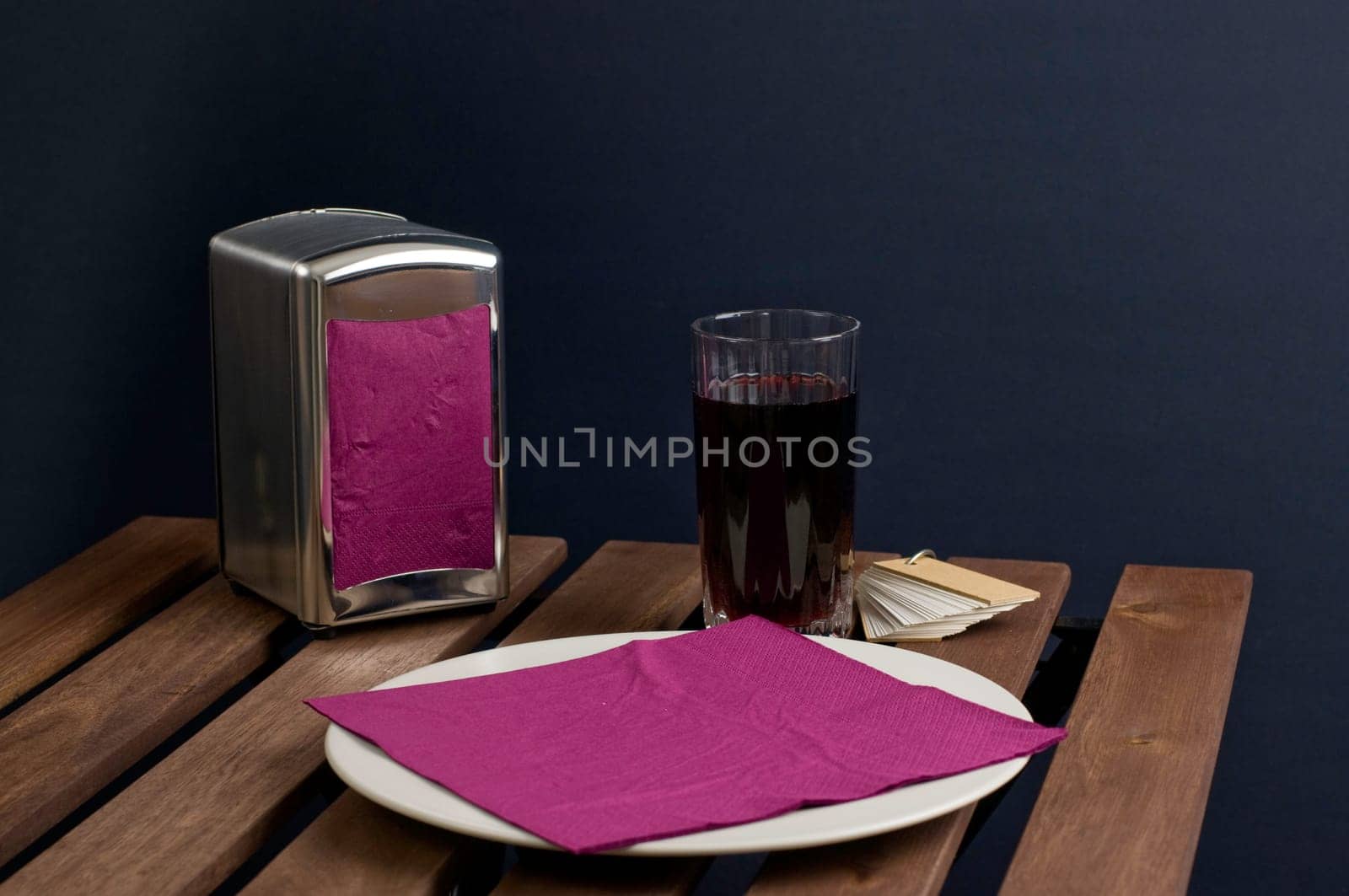 Napkin on china plate and juice in glass on wooden table