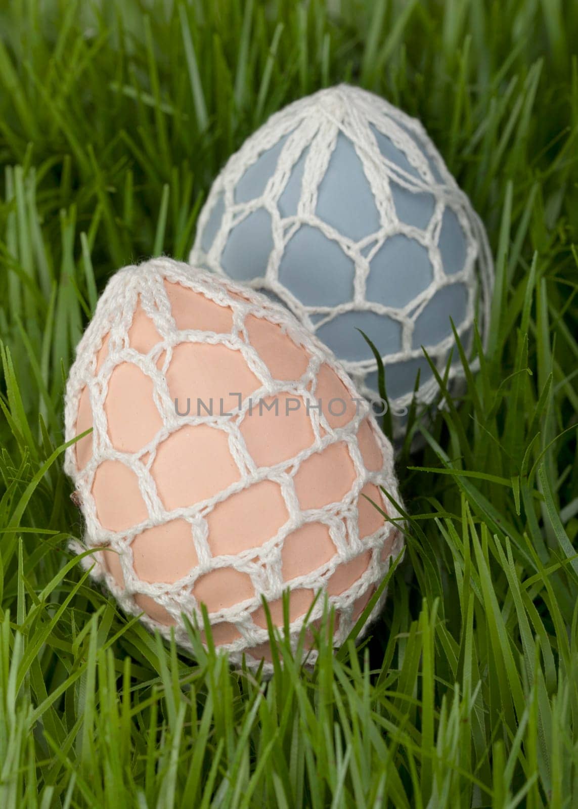 Traditional hand decorated Easter Eggs with an unusual covering of crocheted net nestling in green grass waiting to be found by the children during the Easter Egg Hunt