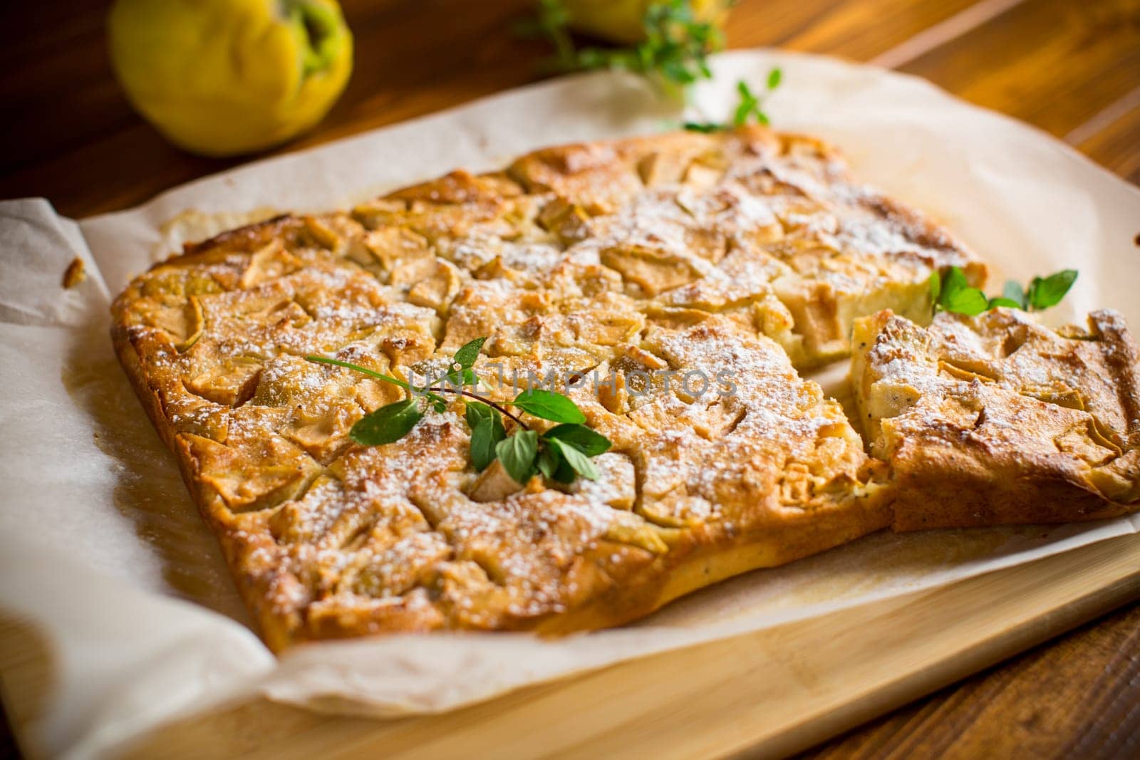 prepared curd semolina pie with quince inside and covered with powdered sugar on a wooden board.