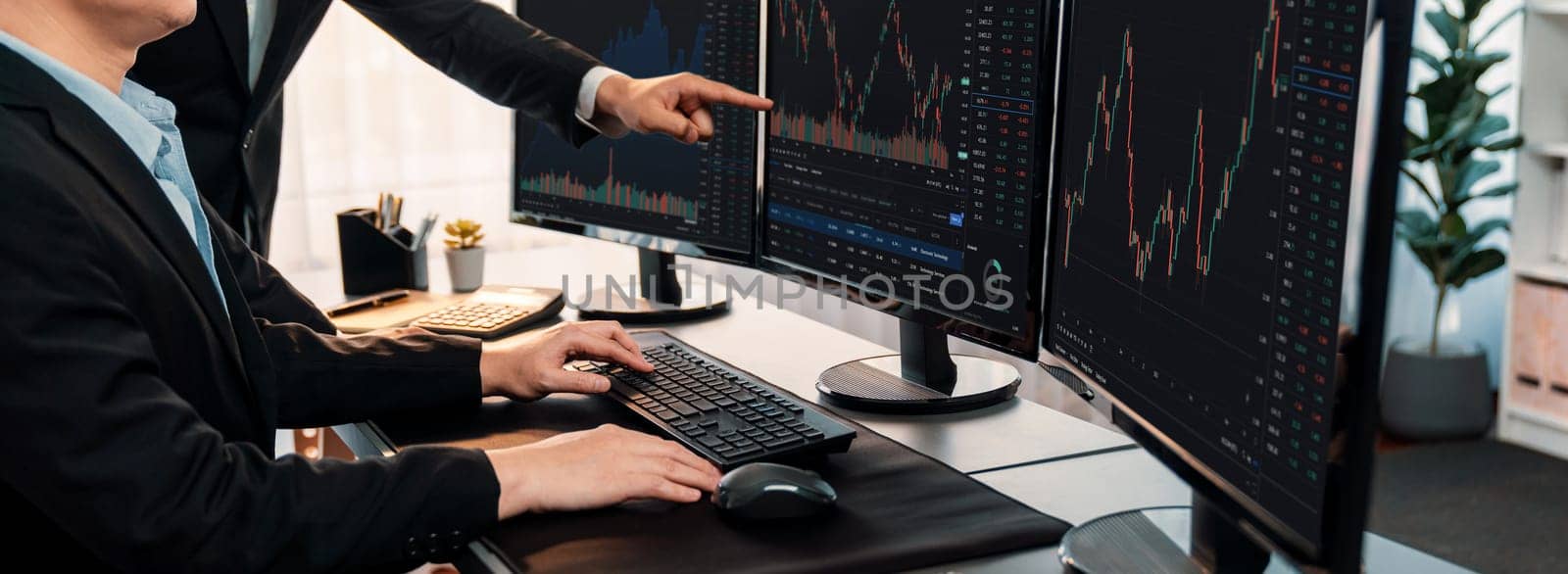 Group of traders discussing on office desk, monitoring stock market on monitor at office workplace. Businessman and broker analyzing stock graph together at stock trading company. Trailblazing